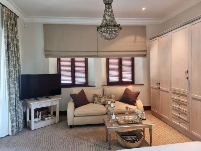 Natural woven roman blind above plantation shutters in a Cape Town lounge