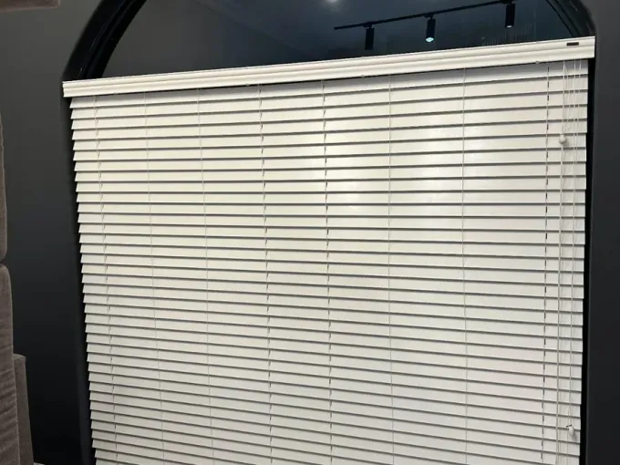 White venetian blinds fitted under an arched window in a Cape Town lounge