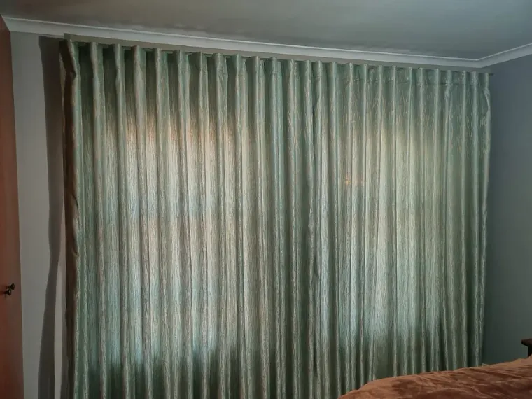 Sage-green wave curtains fitted floor to ceiling in a Cape Town bedroom
