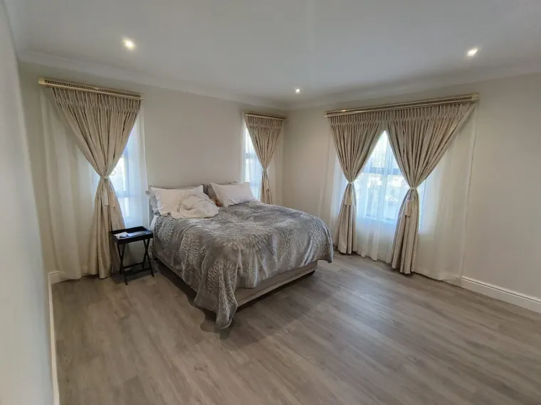 Cream pinch-pleat curtains with sheers and tie-backs in a Cape Town bedroom