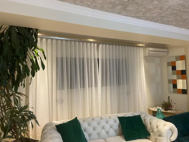 White sheer curtains over a white tufted sofa in a Cape Town lounge