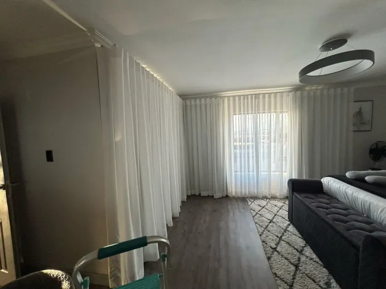 White sheer wave curtains wrapping a corner in a Cape Town bedroom