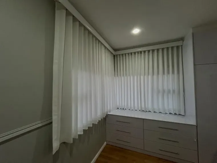 White wave curtains with sheers wrapping a corner over built-in drawers in a Cape Town dressing room
