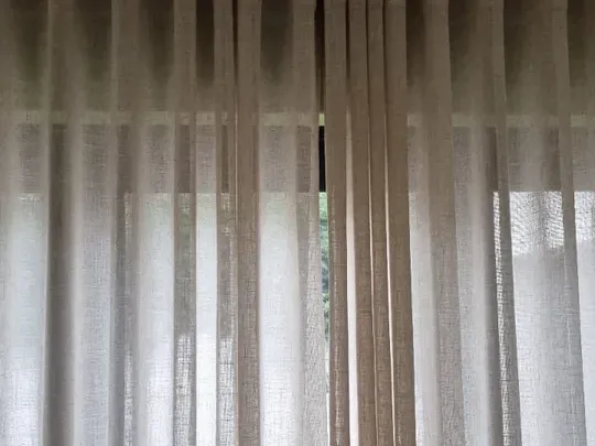 Natural linen-look sheer curtains on a ceiling track, close-up detail