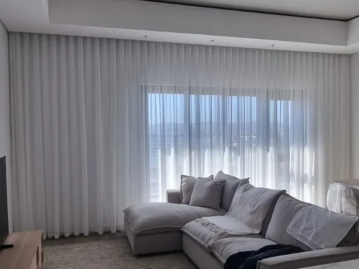 White sheer curtains across a lounge wall with a sea view, Strand, Cape Town